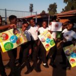 City Year South Africa service leaders smiling holding posters at a school