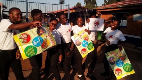 City Year South Africa service leaders smiling holding posters at a school