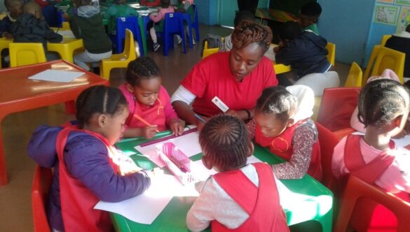 City Year South Africa serving leader working with a table of learners in school